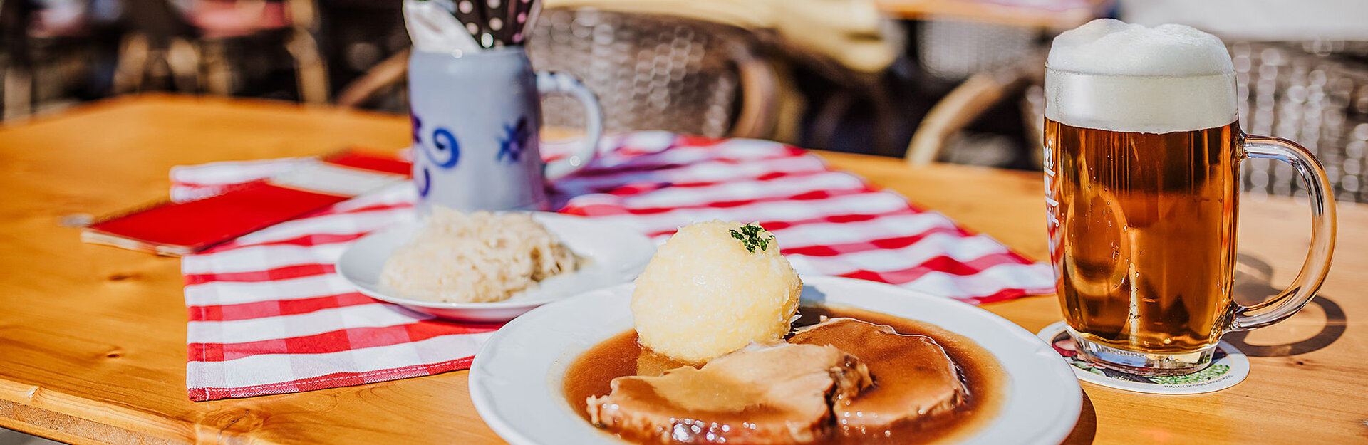 Fränkischer Braten mit Kloß und Bier auf gedecktem Außentisch